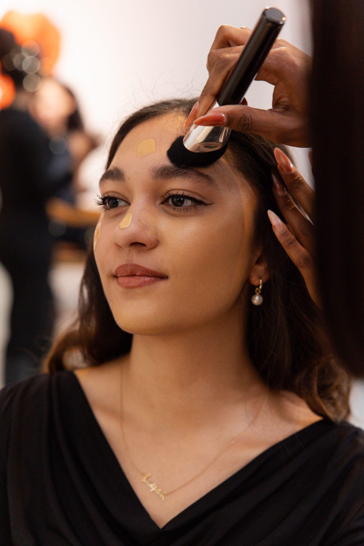 A makeup artist applying foundation with a brush at a Beauty Stamp event